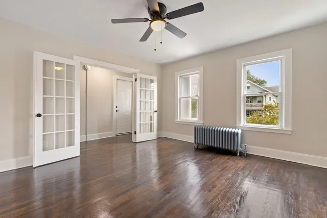 a view of an empty room with a window and wooden floor