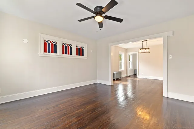 a view of an empty room with window and wooden floor