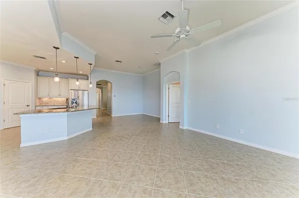 an empty room with wooden floor chandelier fan and windows