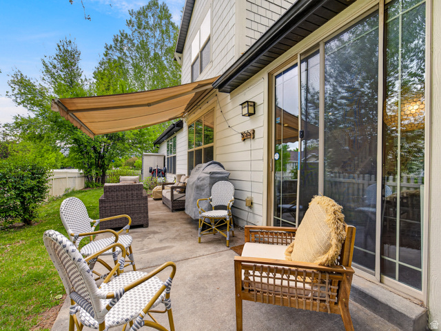 557 Craftsman Way Midway, UT 84049 - Photo 44 of 59 Exterior patio featuring a retractable awning, concrete flooring, sliding glass doors, and shingle siding