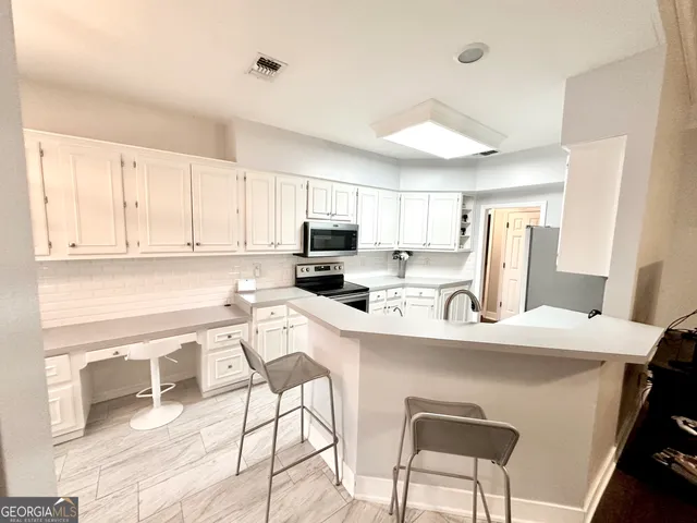 an empty room with wooden floor cabinet and windows