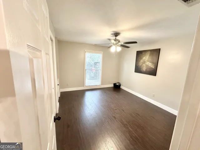 an empty room with wooden floor fan and windows