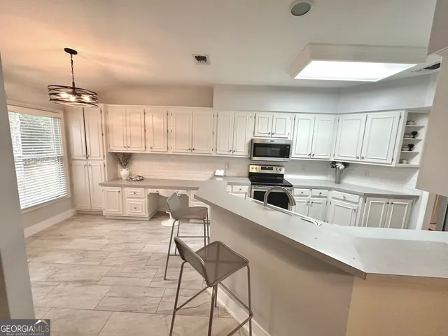 a kitchen with stainless steel appliances a stove a sink a refrigerator and cabinets
