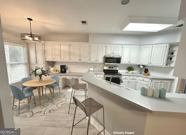 a kitchen with stainless steel appliances granite countertop a stove a sink a refrigerator and white cabinets with wooden floor