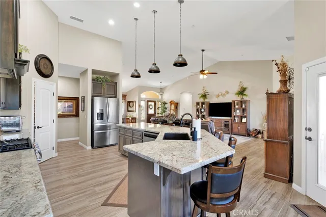 a kitchen with stainless steel appliances kitchen island granite countertop a stove top oven a sink a counter space and cabinets