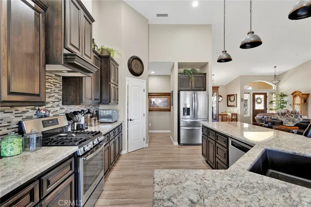 a kitchen with stainless steel appliances granite countertop a sink a stove and a wooden floors