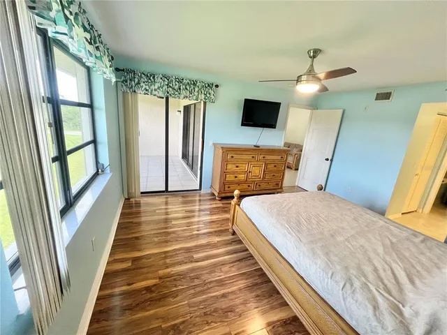 a bedroom with a bed wooden floor and a flat tv screen