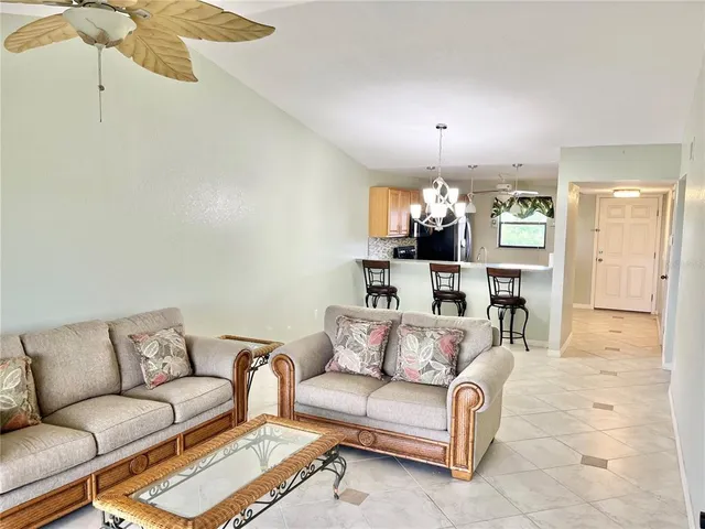 a living room with furniture a chandelier and kitchen view