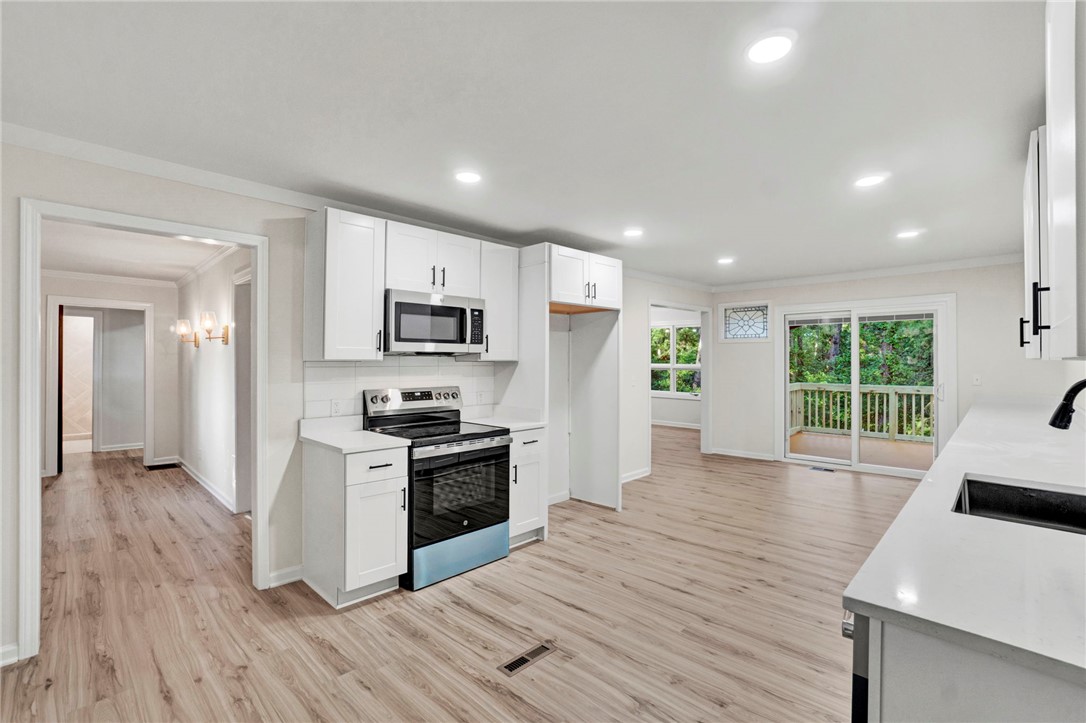 237 Earle Road Central, SC 29630 - Photo 12 of 24 A contemporary kitchen features bright white cabinetry and an open-concept flow to a balcony with green views.