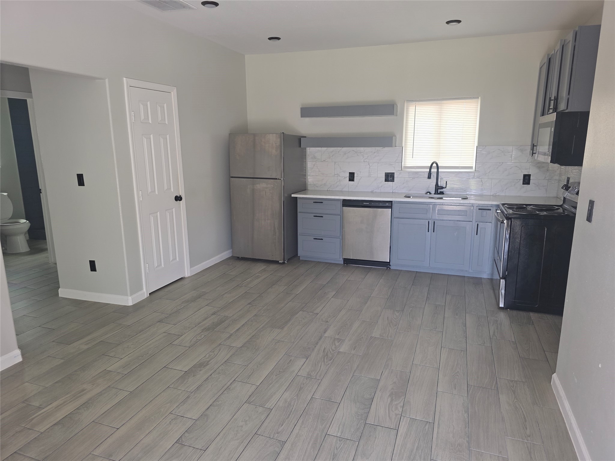 3221 Ennis Street, Unit A Houston, TX 77004 - Photo 2 of 8 a kitchen with a sink a refrigerator a window and cabinets