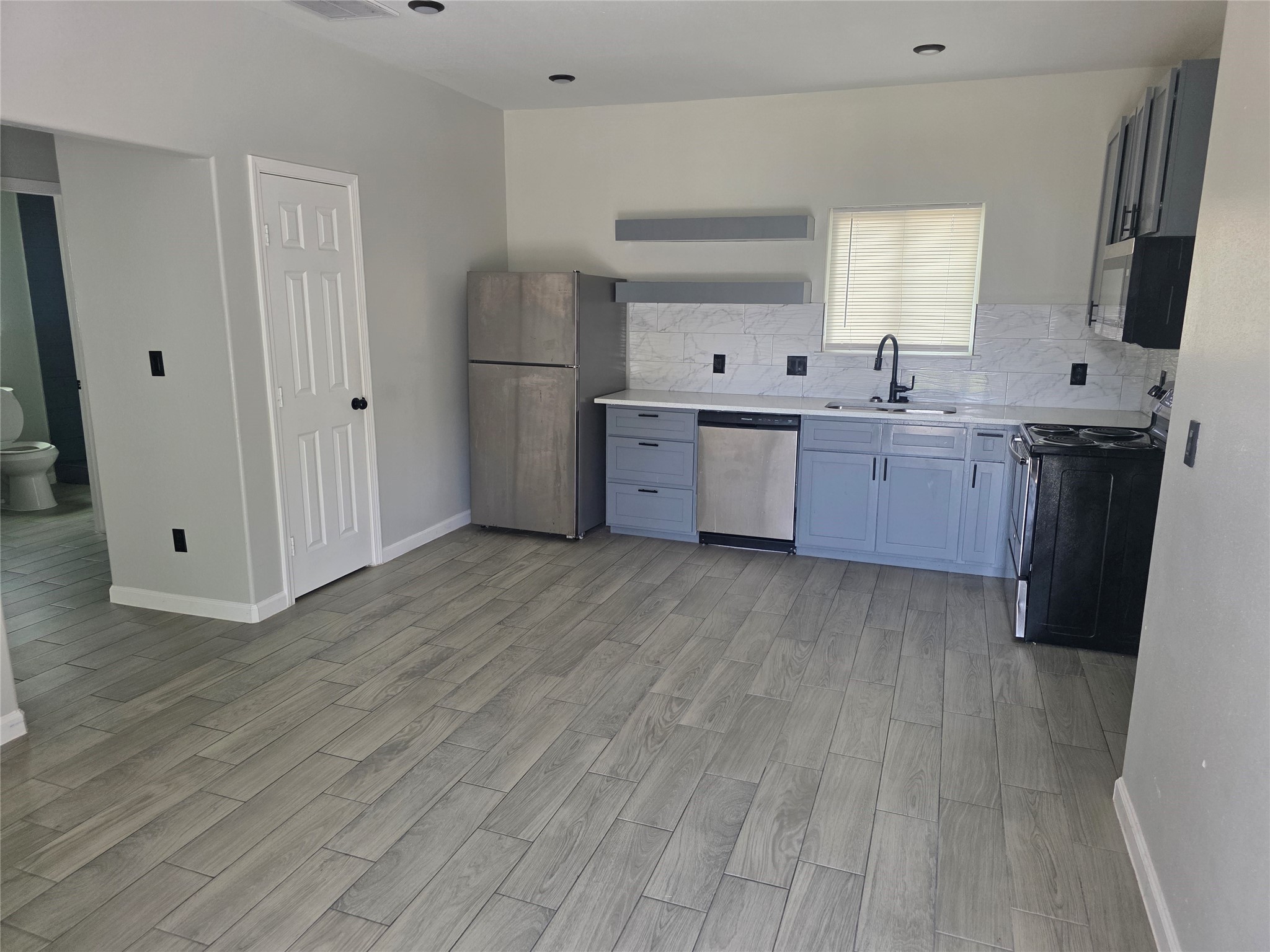 3221 Ennis Street, Unit A Houston, TX 77004 - Photo 5 of 8 a kitchen with stainless steel appliances a refrigerator sink and cabinets