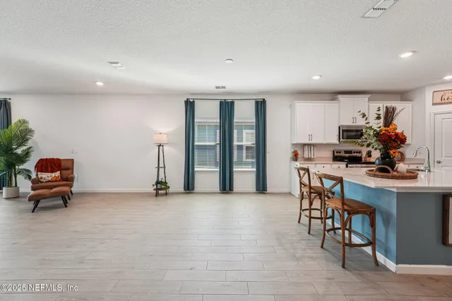 a kitchen with stainless steel appliances a stove a sink a refrigerator white cabinets and wooden floor