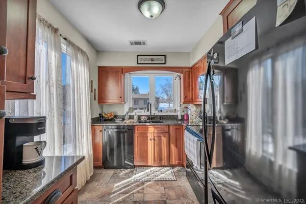 a kitchen with stainless steel appliances granite countertop a refrigerator a stove and a sink with wooden floor