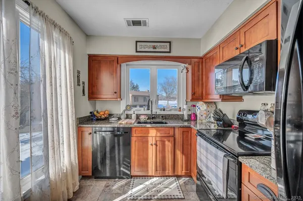 a kitchen with stainless steel appliances granite countertop a stove a sink and a refrigerator