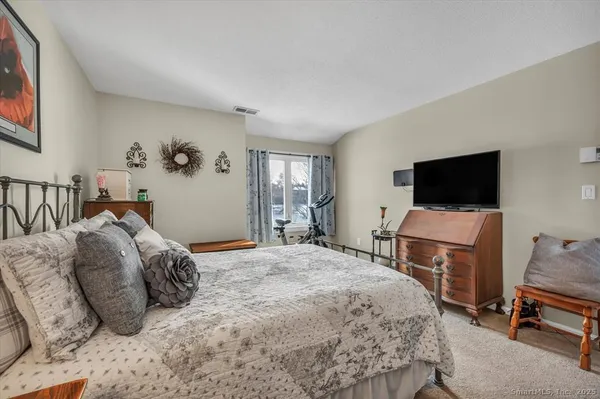 a bedroom with a bed a computer on the desk and a flat screen tv