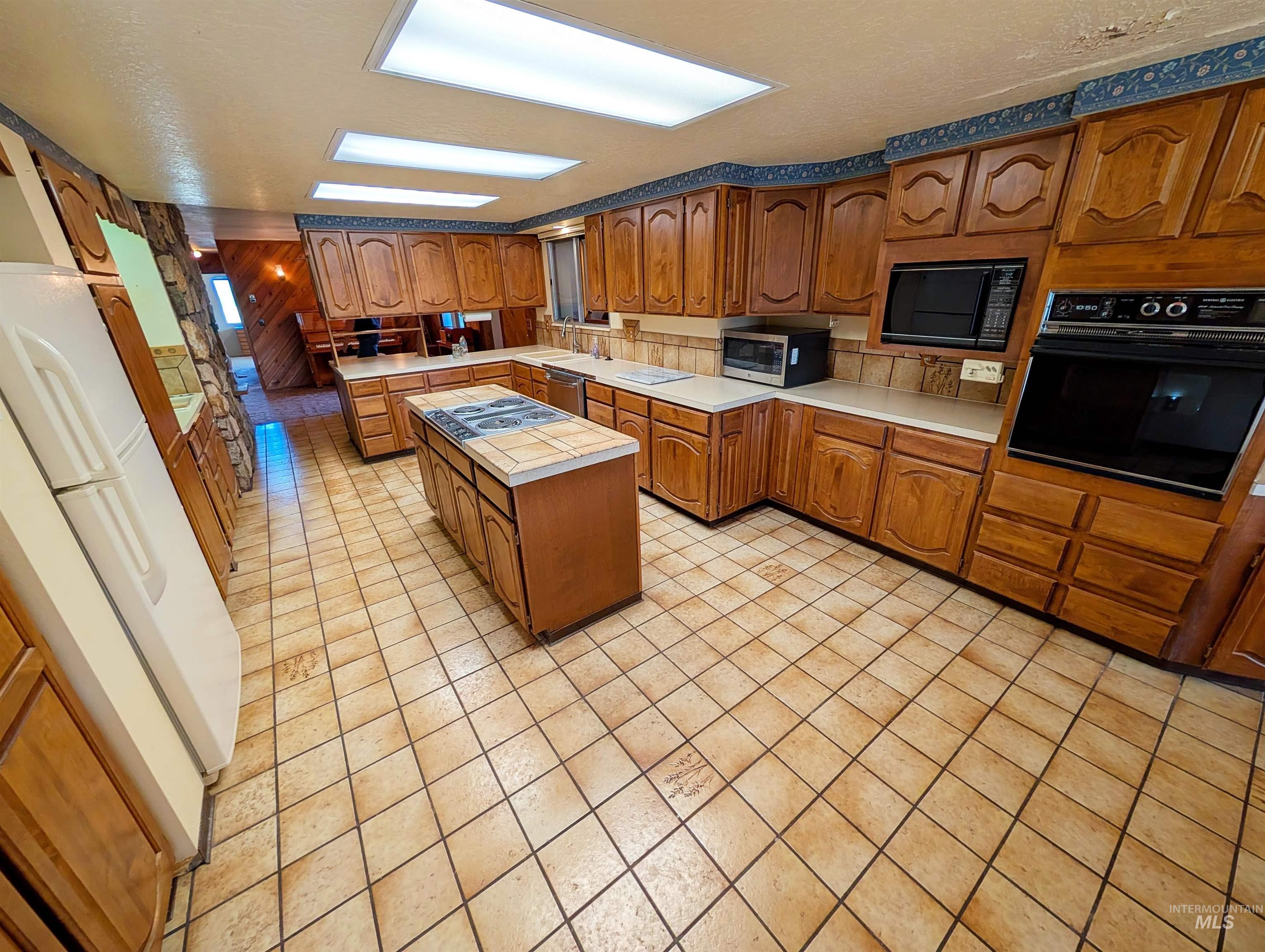 11100 Bens Road Cascade, ID 83611 - Photo 15 of 35 Expansive kitchen featuring wood cabinetry, a central island with a built-in cooktop, and an integrated wall oven