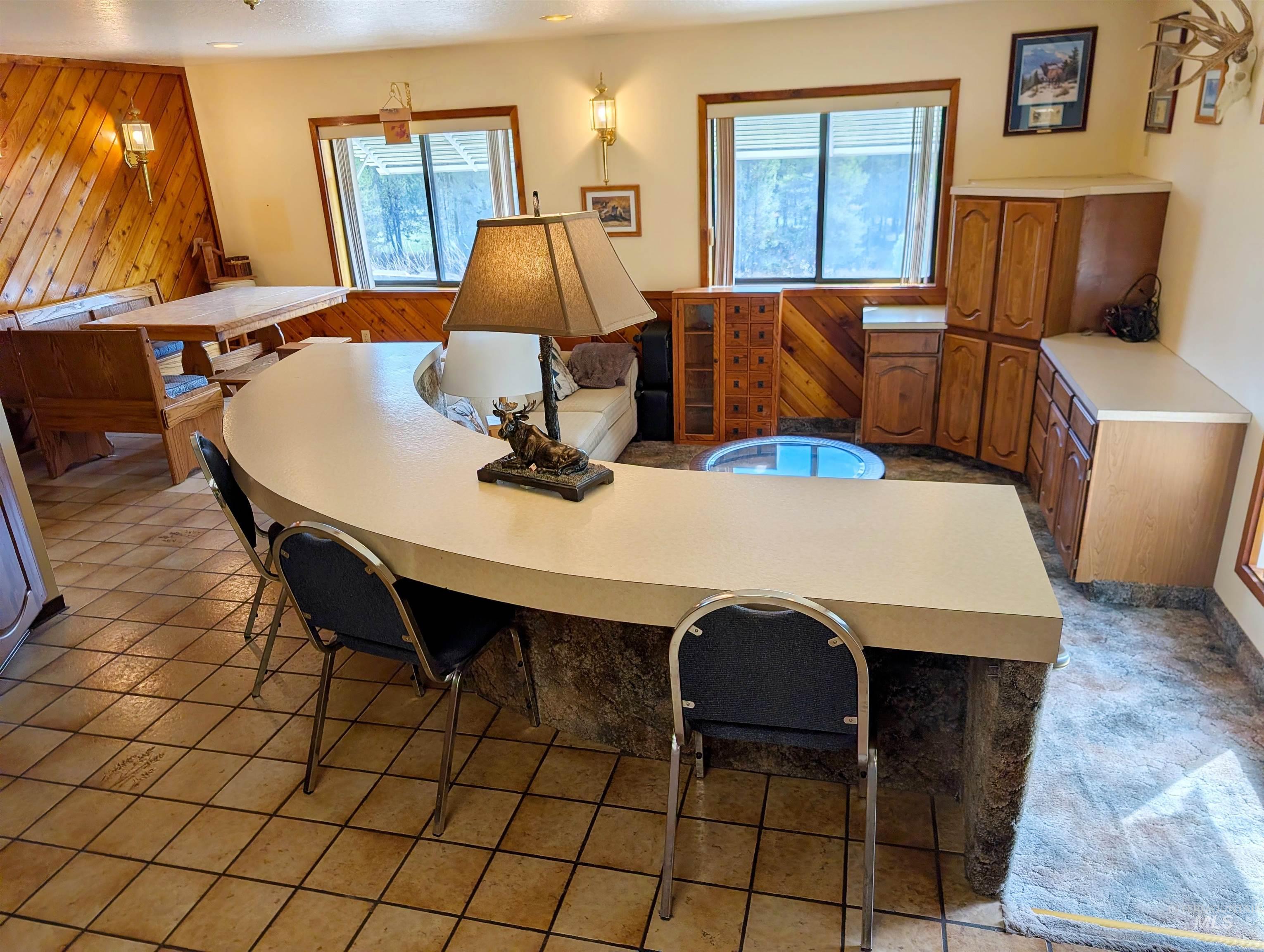 11100 Bens Road Cascade, ID 83611 - Photo 17 of 35 Curved countertop bar seating area featuring a built-in bench dining nook with wood paneling, multiple windows, and a range of cabinetry