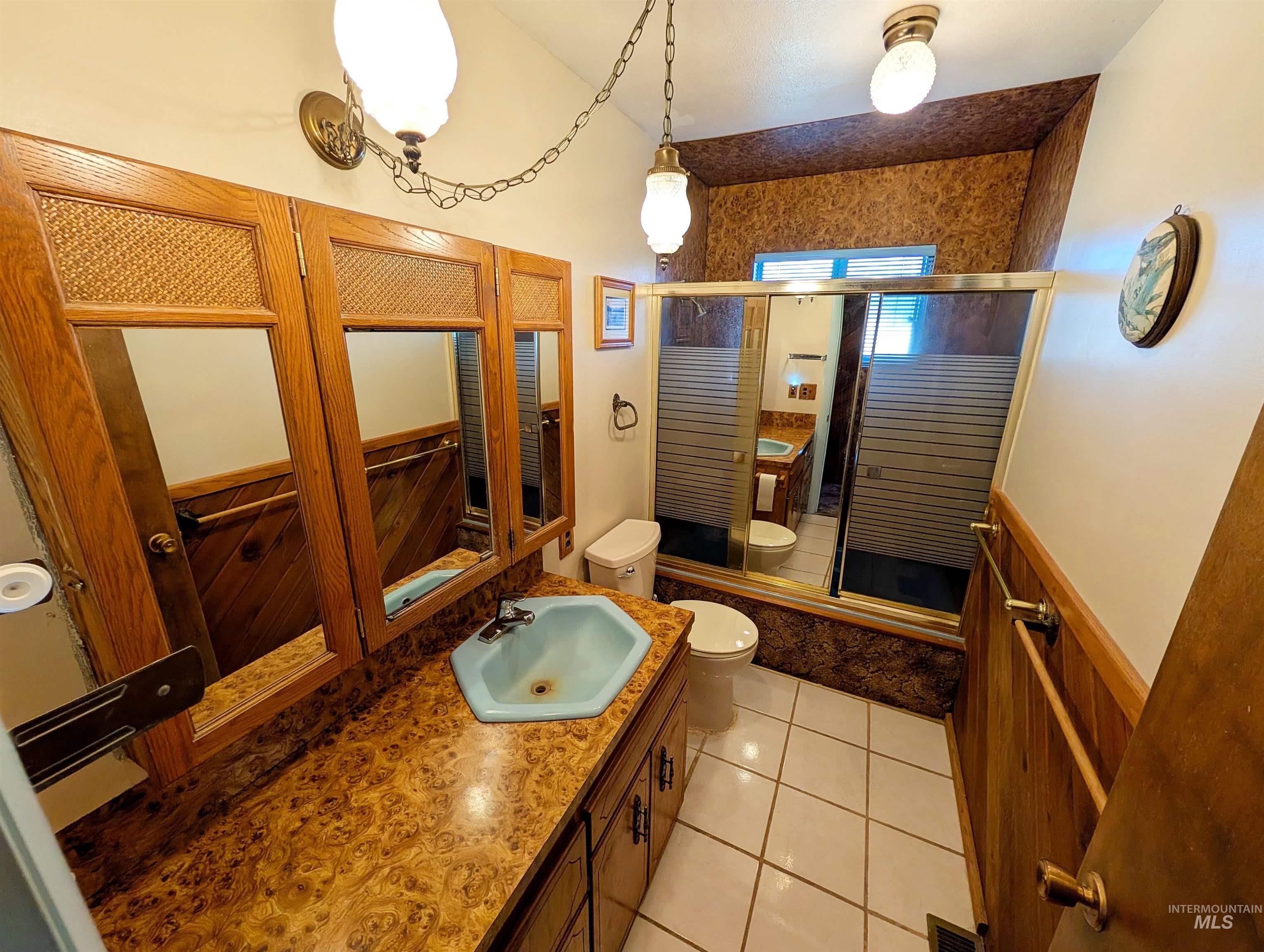 11100 Bens Road Cascade, ID 83611 - Photo 27 of 35 Bathroom featuring a light blue hexagonal sink, wood-finish vanity with ample storage, and a patterned countertop