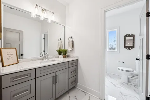 a bathroom with a granite countertop sink a toilet and a mirror