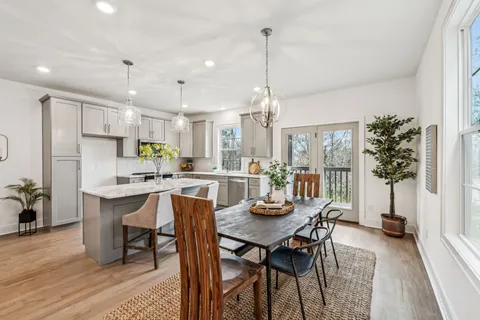 a view of a dining room and livingroom with furniture wooden floor a chandelier