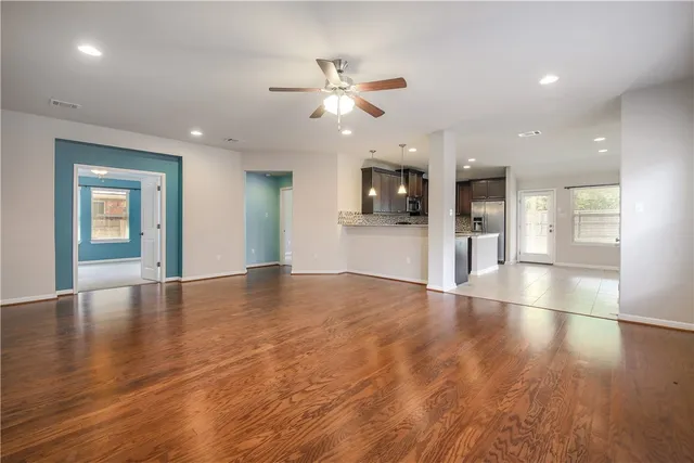 an empty room with wooden floor and windows