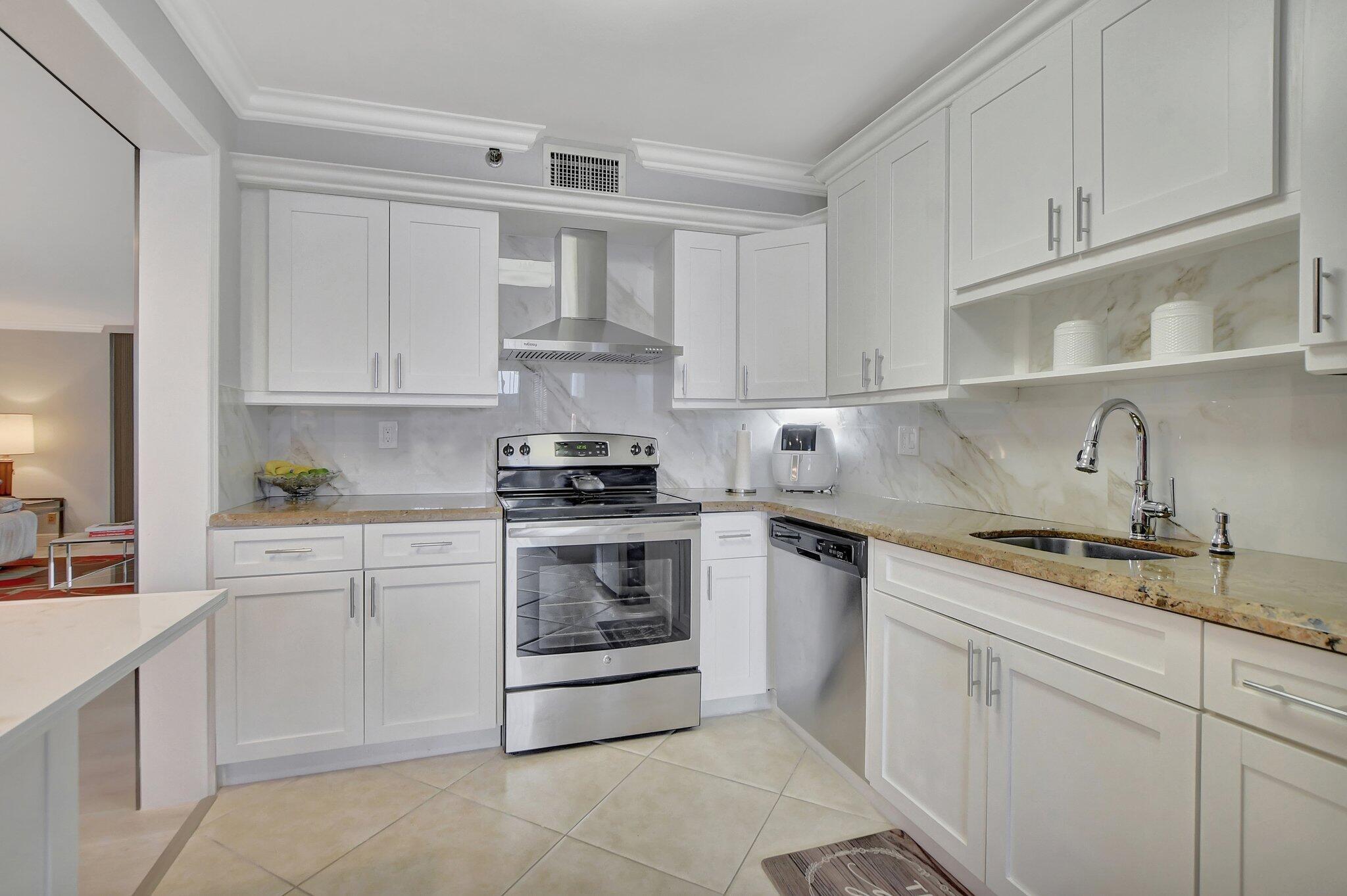 7194 Promenade Drive, Unit 102 Boca Raton, FL 33433 - Photo 15 of 56 a kitchen with granite countertop white cabinets and white appliances