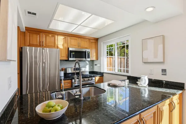 a kitchen with stainless steel appliances granite countertop a sink a stove counter space and a window