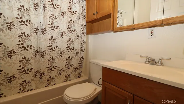 a bathroom with a granite countertop sink and a toilet