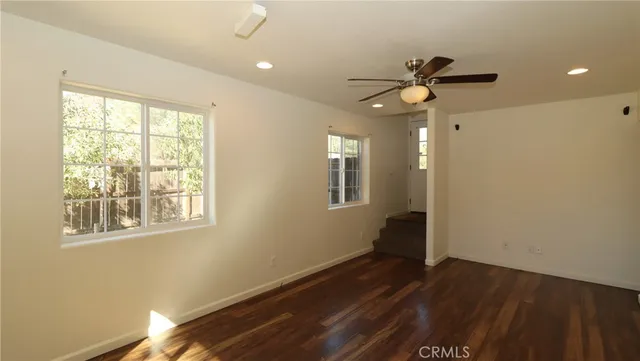 a view of an empty room with a window and wooden floor