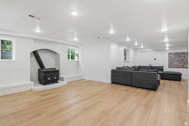 4150 Dover Lane Provo, UT 84604 - Photo 25 of 44 Spacious room featuring a white painted brick fireplace with a black wood stove insert, light wood-finish flooring, and recessed ceiling lighting