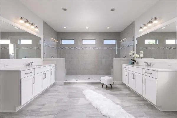 a large bathroom with a double vanity sink a toilet a mirror and shower