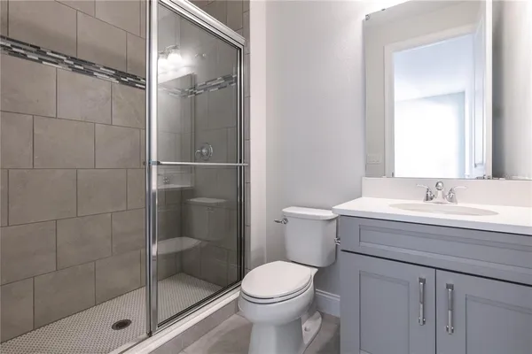 a bathroom with a shower sink vanity mirror and toilet