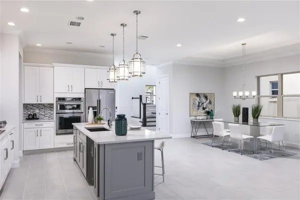a kitchen with stainless steel appliances kitchen island granite countertop a refrigerator a stove a sink a oven and a dining table with wooden floor