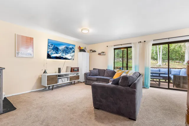 a living room with furniture a flat screen tv and a floor to ceiling window