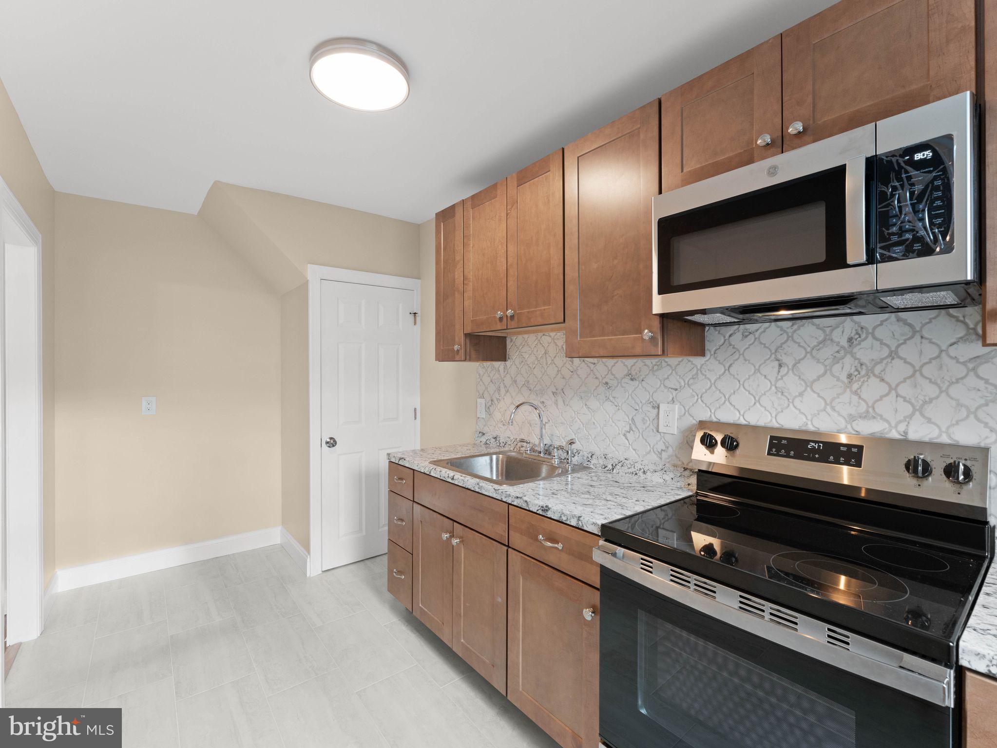 7510 Rugby Street Philadelphia, PA 19150 - Photo 7 of 22 a kitchen with stainless steel appliances a stove a microwave and sink