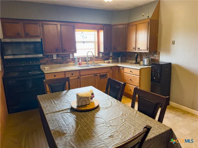 a kitchen with a sink a window and chairs