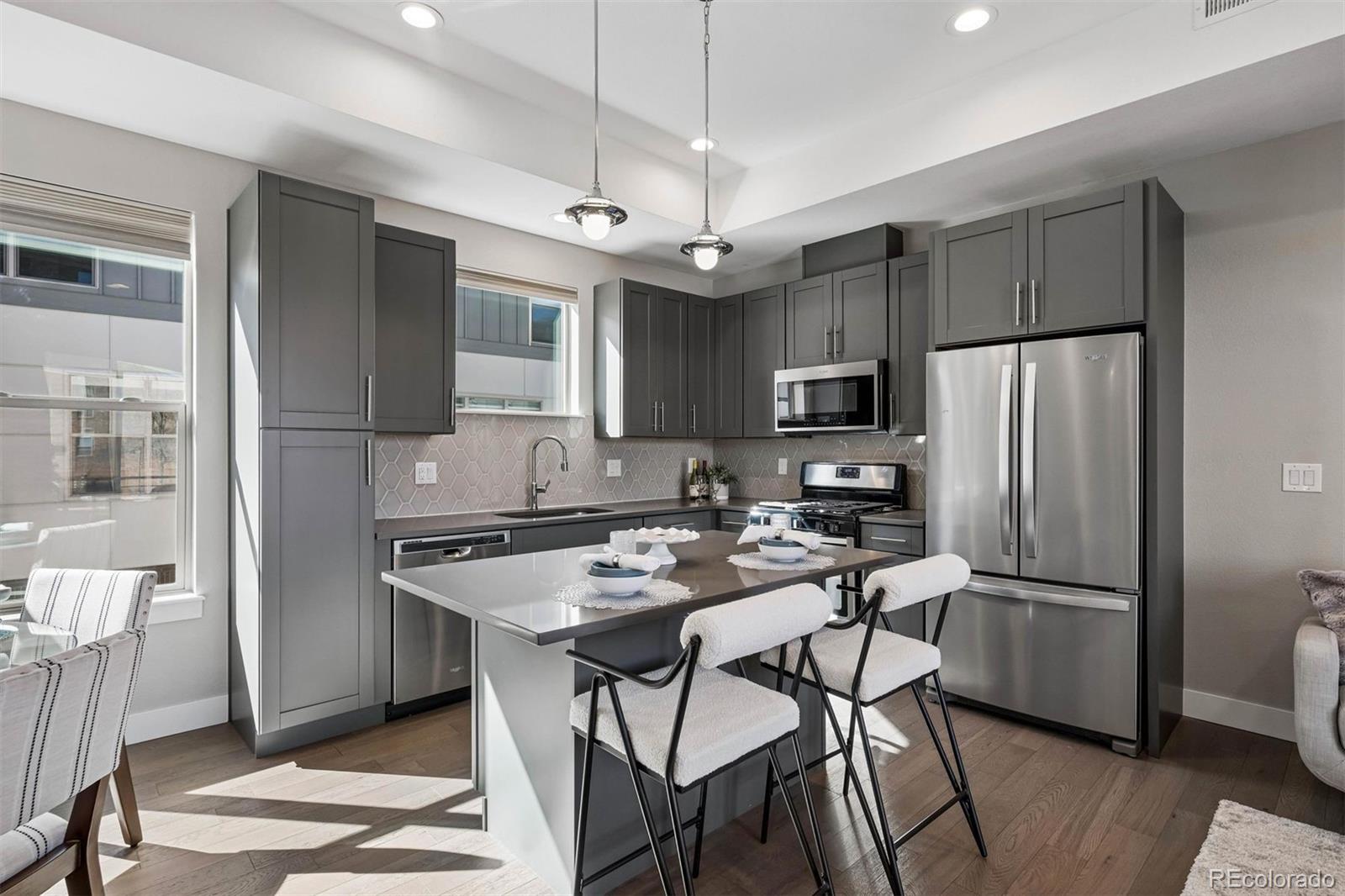 5366 Allison Street, Unit D Arvada, CO 80002 - Photo 16 of 28 a kitchen with stainless steel appliances granite countertop a refrigerator a stove a sink a dining table and chairs with wooden floor
