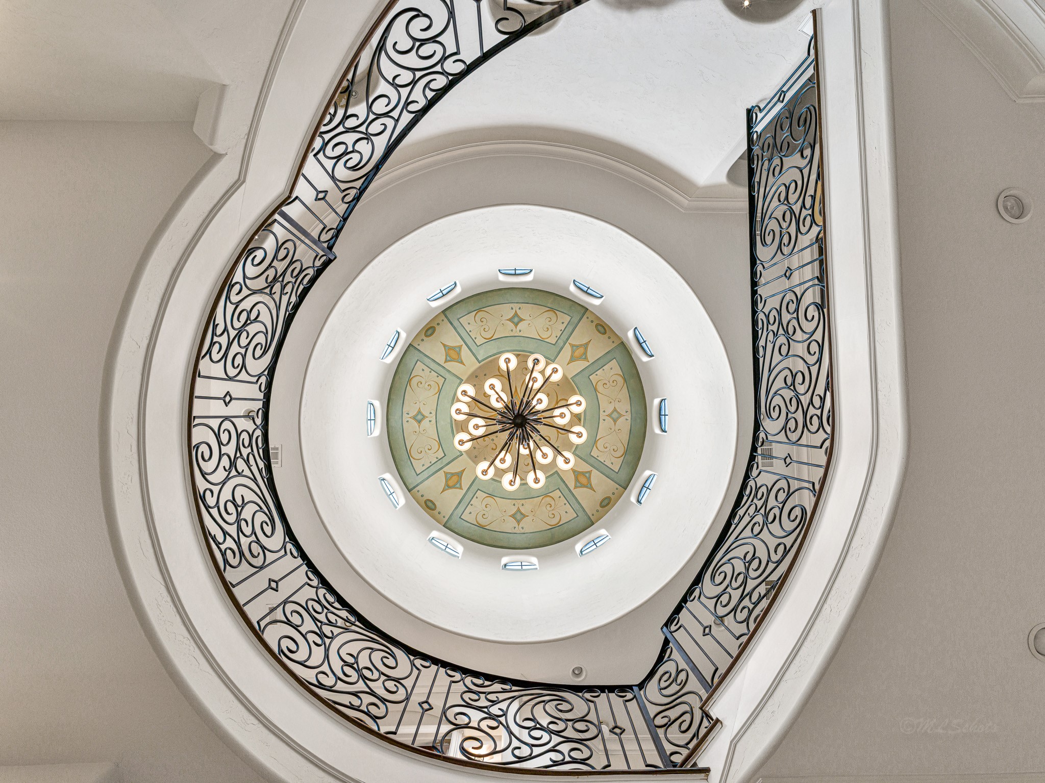 4614 Inker Street Houston, TX 77007 - Photo 3 of 36 A stunning spiral staircase with elegant wrought iron railings, leading up to a beautifully designed circular ceiling with a central chandelier. The intricate details and open design create a luxurious and airy feel.