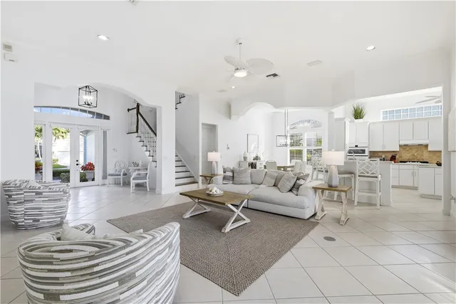 a room with lots of white furniture and a chandelier