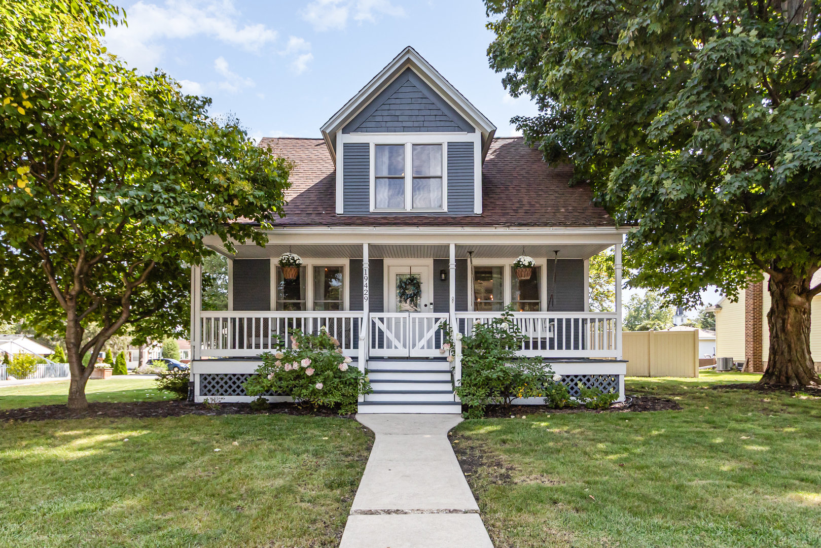 a front view of a house with a garden and trees