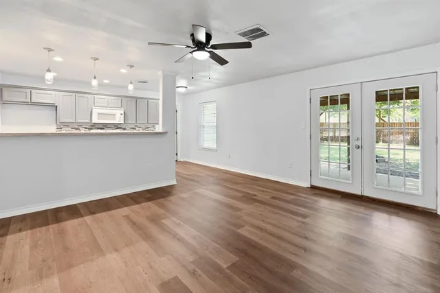 a view of an empty room with a window and wooden floor