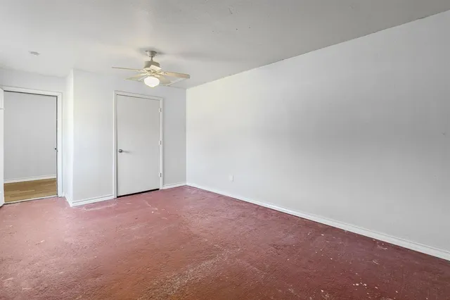 an empty room with a chandelier fan and windows
