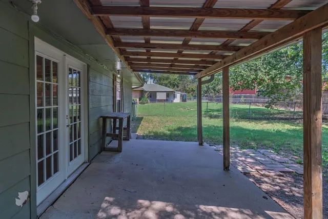 a view of a porch with wooden floor and roof with a garden