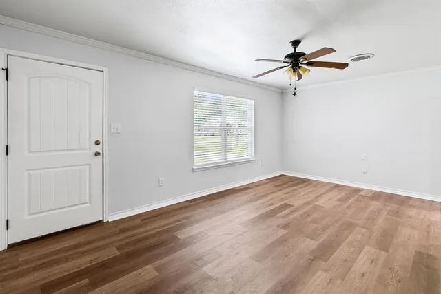 a view of empty room with wooden floor and fan