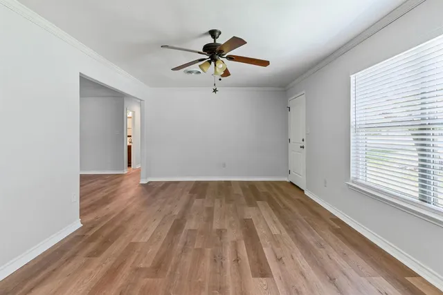 a view of empty room with wooden floor and fan