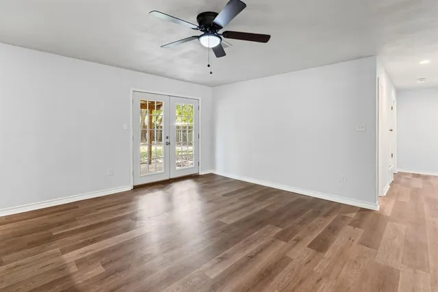 a view of an empty room with window and wooden floor