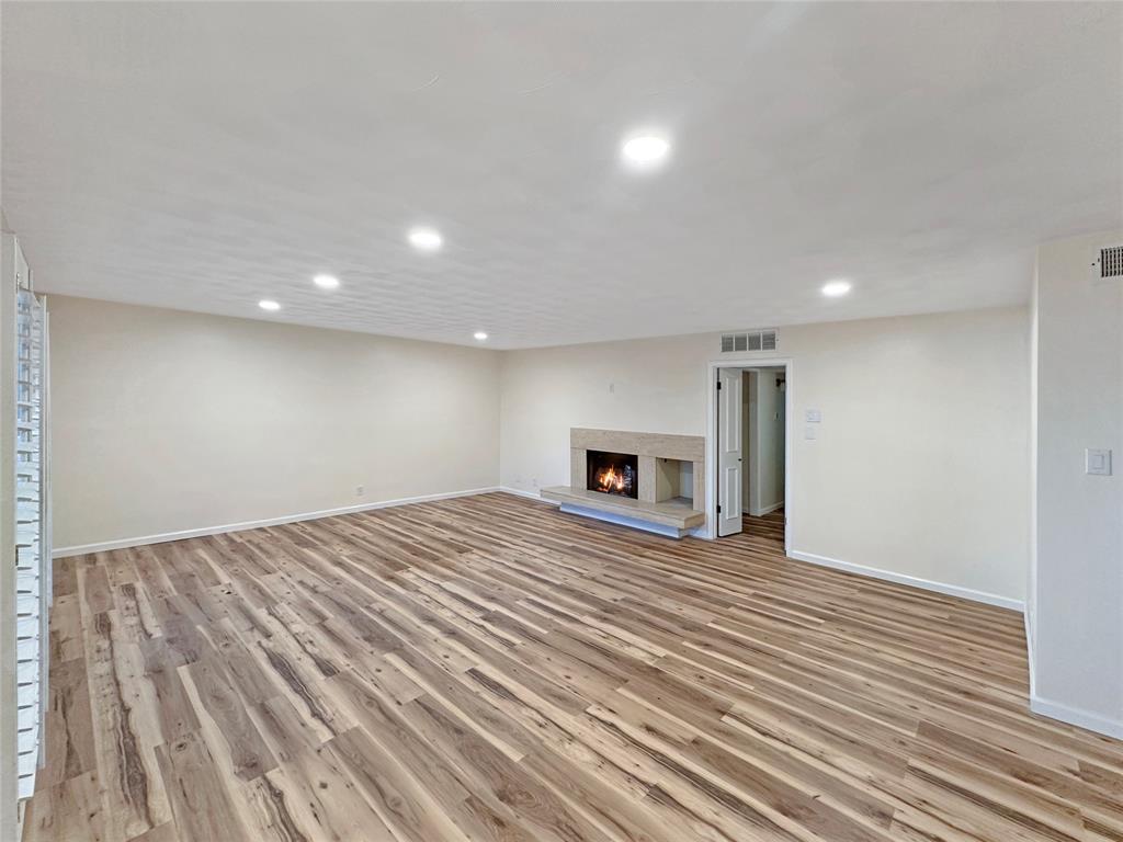 2301 Ridgmar Plaza, Unit 5 Fort Worth, TX 76116 - Photo 2 of 20 Living room featuring light wood finished floors, a lit fireplace, and recessed lighting