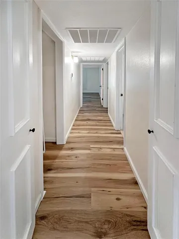 a view of a hallway with wooden floor and staircase