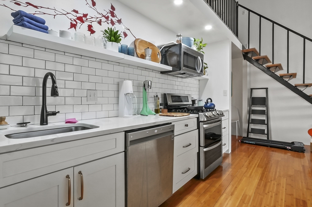 156 Porter Street, Unit 246 Boston, MA 02128 - Photo 4 of 25 a kitchen with stainless steel appliances a sink dishwasher stove and white cabinets with wooden floor