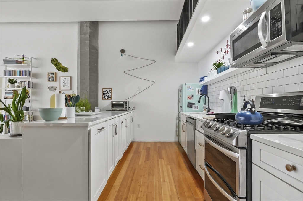 156 Porter Street, Unit 246 Boston, MA 02128 - Photo 6 of 25 a kitchen with stainless steel appliances granite countertop a lot of cabinets a stove and a wooden floors